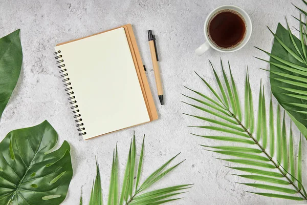 White blank note paper and big green tropical leaves on background. Flat lay. Top view. Copy space. Royalty Free Stock Images