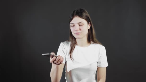 Eine junge Frau, die mit einem Mobiltelefon durch ein soziales Netzwerk scrollt, schockiert von einem Gerät oder einer App. — Stockvideo