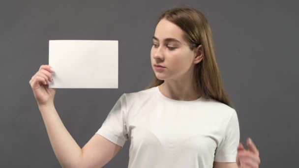 흰색 티셔츠를 입고 있는 행복 한 소녀의 모습, 그 장소 의빈 복사본에 그녀의 손을 보여 주고 광고나 광고 텍스트의 위치를 보여 줍니다. — 비디오