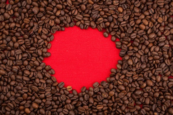 Кофейные зёрна на красном фоне — стоковое фото