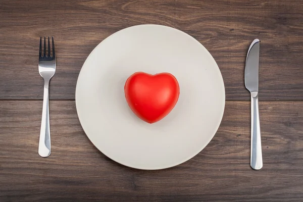 Coeur sur une assiette, une fourchette et un couteau — Photo