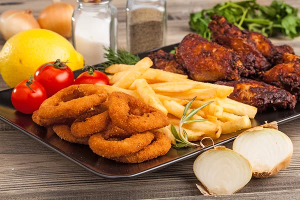 Anéis de cebola, batatas fritas e asas de frango — Fotografia de Stock