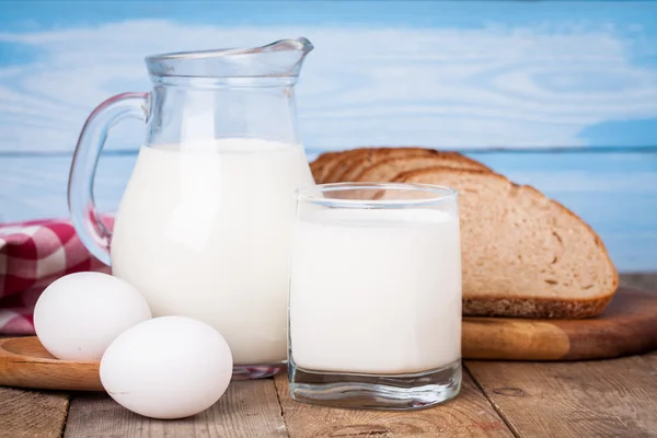 Chleb, jaja i mleko szkła na drewnianym stole — Zdjęcie stockowe