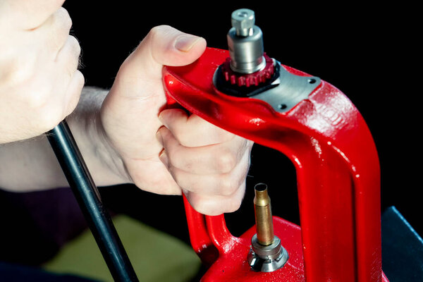 Красный пресс и снаряд на темном фоне, мягкая фокусировка. Принято. Процесс изготовления патрона для винтовки