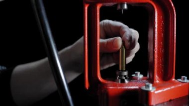 Tüfek fişeği yapma süreci. El presi ve mühimmat kovanı koyu arka plana karşı, yumuşak odaklı. Boşluğu kopyala