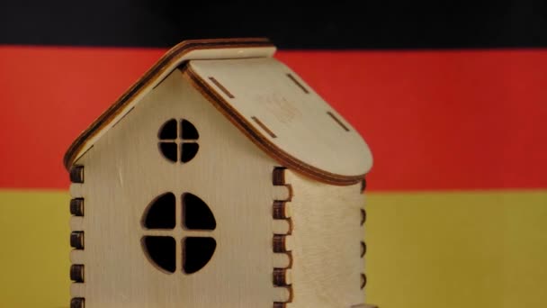 Malý dřevěný domek, německá vlajka na pozadí. Koncept nemovitostí, měkké zaměření — Stock video