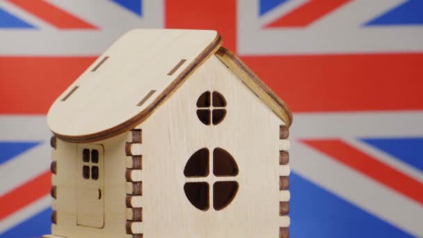 Malý dřevěný domek, na pozadí vlajka Velké Británie. Koncept nemovitostí, měkké zaměření — Stock video