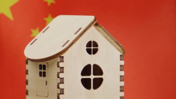 Μικρό ξύλινο σπίτι, σημαία της Κίνας στο παρασκήνιο. έννοια της ακίνητης περιουσίας, μαλακό εστίαση — Αρχείο Βίντεο