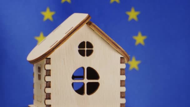 Malý dřevěný domek, vlajka Evropské unie na pozadí. Koncept nemovitostí, měkké zaměření — Stock video