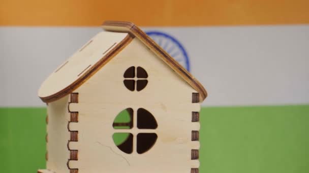 Небольшой деревянный дом, флаг Индии на заднем плане. Концепция недвижимости, мягкий фокус — стоковое видео
