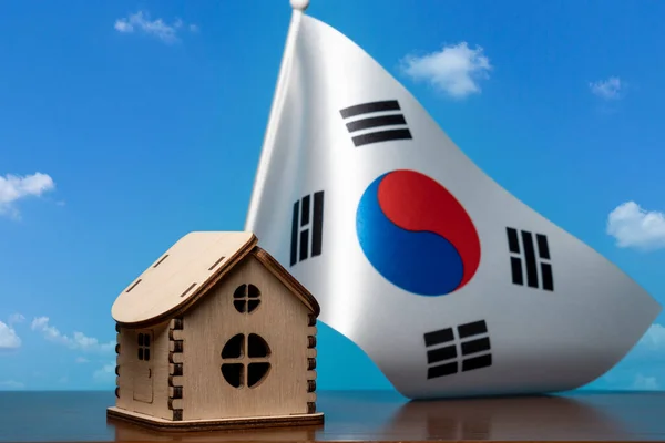 Küçük ahşap ev ve Kore Cumhuriyeti bayrağı, arka planda gökyüzü. Emlak kavramı, kopyalama alanı — Stok fotoğraf