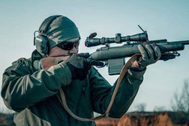 Tüfekli bir nişancının portresi. Avrupalı optik görüşlü bir tüfek ateşliyor