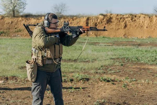 Blanke man in militair uniform schiet een AK op een schietbaan — Stockfoto