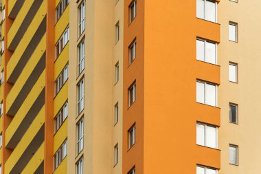 Modern bir şehrin mimarisinin bir parçası olarak pencereleri ve balkonları olan çok katlı bir binanın ön cephesi.