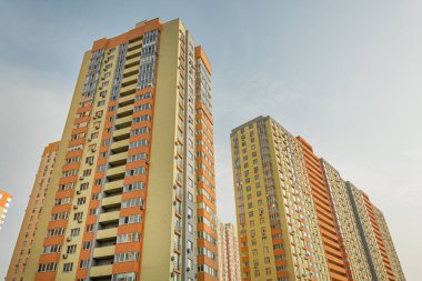 Modern bir şehrin mimarisinin bir parçası olarak pencereleri ve balkonları olan çok katlı bir binanın ön cephesi.