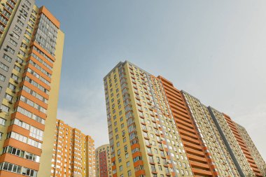 Modern bir şehrin mimarisinin bir parçası olarak pencereleri ve balkonları olan çok katlı bir binanın ön cephesi.