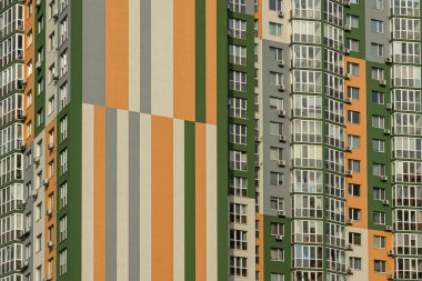 Modern bir şehrin mimarisinin bir parçası olarak pencereleri ve balkonları olan çok katlı bir binanın ön cephesi.