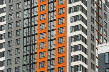 Modern bir şehrin mimarisinin bir parçası olarak pencereleri ve balkonları olan çok katlı bir binanın ön cephesi.