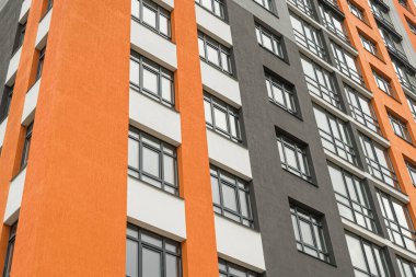 Modern bir şehrin mimarisinin bir parçası olarak pencereleri ve balkonları olan çok katlı bir binanın ön cephesi.