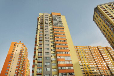 Modern bir şehrin mimarisinin bir parçası olarak pencereleri ve balkonları olan çok katlı bir binanın ön cephesi.