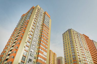 Modern bir şehrin mimarisinin bir parçası olarak pencereleri ve balkonları olan çok katlı bir binanın ön cephesi.