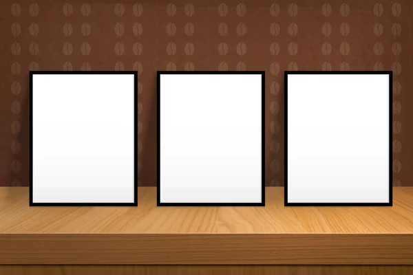 Three blank poster stand on a wooden table over vintage wallpape — Stock Photo, Image