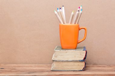 Kitap kule ve turuncu kupa ile renkli kalemler