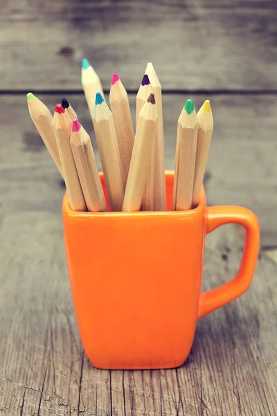 Lápices de color en una taza naranja — Foto de Stock