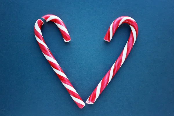 Candy canes in a heart shape on blue background — Stock Photo, Image