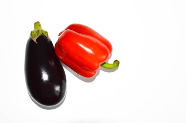 Olgun sebzeler. Beyaz arka planda kırmızı dolma biber ve mor patlıcan..