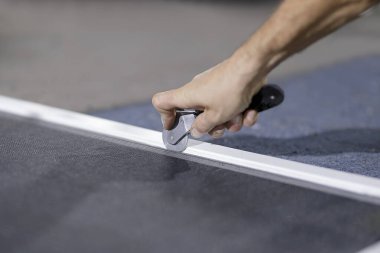 Pencere perdesi yapan bir adam. Sivrisinek ağı takmak için tekerlek aletli bir adamın elini görebilirsiniz..