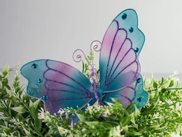 大的紫色和蓝色网纹蝴蝶 在白色和绿色的植物之上 有闪光和宝石与白色的背景 完美的春天 — 图库照片