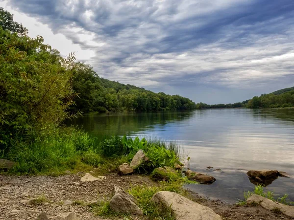 Keystone Gölü, Laurel Highlands, West Moreland County, Pennsylvania 'da yaz sonlarında mavi gökyüzü ve sahil boyunca durgun su ile birlikte güneş batmadan hemen önce..