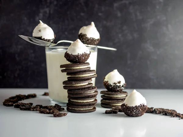 Cookies & Cream Cake Balls, truffle like dessert with a fresh glass of cold milk, a silver spoon, chocolate sandwich cookies and cookie crumbs.