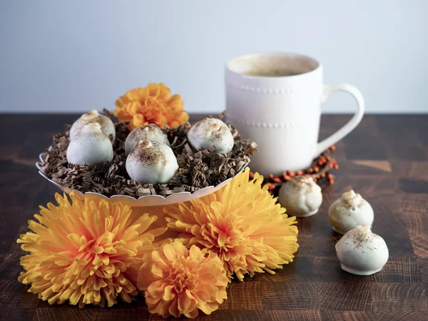 Cappuccino kek topları, tatlı gibi kahve aromalı trüf, beyaz seramik kahve fincanı ve kâseleriyle ahşap bir masada portakal çiçekleriyle süslenmiş..  