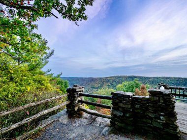 Dağlara ve Batı Virginia 'daki Cooper' s Rock State Ormanı 'ndaki sonbahar yeşilliklerine bir yönde altın gökyüzü, diğer yönde mavi bir girdap ve kayalık uçurum..