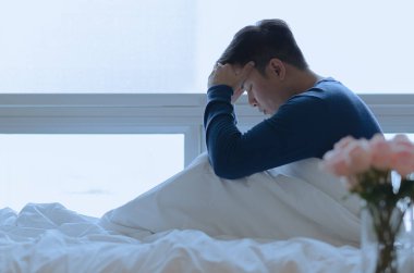 Oturan ve yatakta depresif hisseden bir insan. Depresyon ve yalnızlık kavramı.