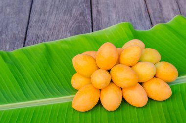 Marian eriği ya da Ma Yong Chid (Taylandca) eriğe benzer ama tadı muz yaprağı arkaplanındaki mango gibidir..