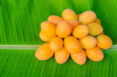 Marian eriği ya da Ma Yong Chid (Taylandca) eriğe benzer ama tadı muz yaprağı arkaplanındaki mango gibidir..