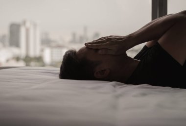 Asyalı bir adam şehrin arka planında yalnız başına üzgün hisseder. Evde kal, depresyon ve yalnızlık kavramı.