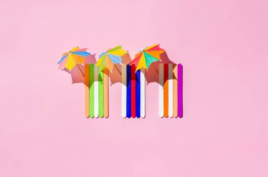 Pembe kumsalda güneş şemsiyeli renkli plaj havluları. Asgari yaz konsepti.