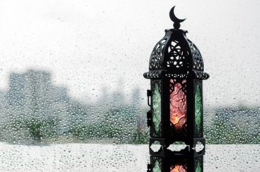 Üzerinde ay sembolü olan fenerler İslami yeni yıl için yağmur damlalarıyla pencereye konur..