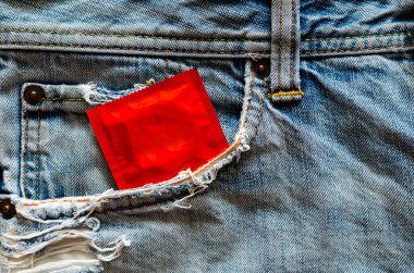 Güvenli seks, cinsel sağlık ve AIDS günü konsepti için kot pantolonun cebinde kondom..
