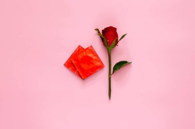 En az güvenli seks, cinsel sağlık ve AIDS günü konsepti için aşk biçimi olarak belirlenmiş prezervatif paketli kırmızı gül..