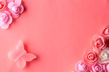 Güzel küçük çiçekler ve bir kelebek pembe bir arka planda yatıyor.