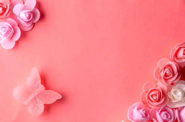 Güzel küçük çiçekler ve bir kelebek pembe bir arka planda yatıyor.