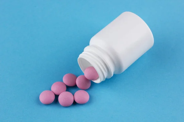 Masadaki beyaz şişeden pembe haplar döküldü.