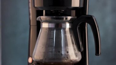 Kahve makinesinden taze kokulu kahve dökülüyor.