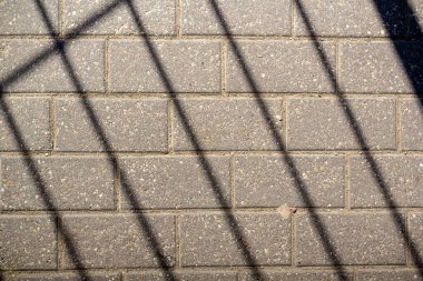 Gri asfalt levhalar ve ızgaranın gölgesi