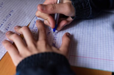 Çocuk bir deftere yazıyor. Çocuk ev ödevi yapıyor. Kalem ve defter. 